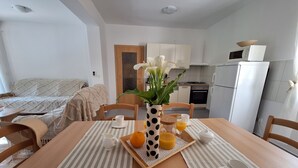 A modern kitchen with white appliances, a dining table set with white cups and a tray of orange juice. - House Bella Vista (Vinodol)