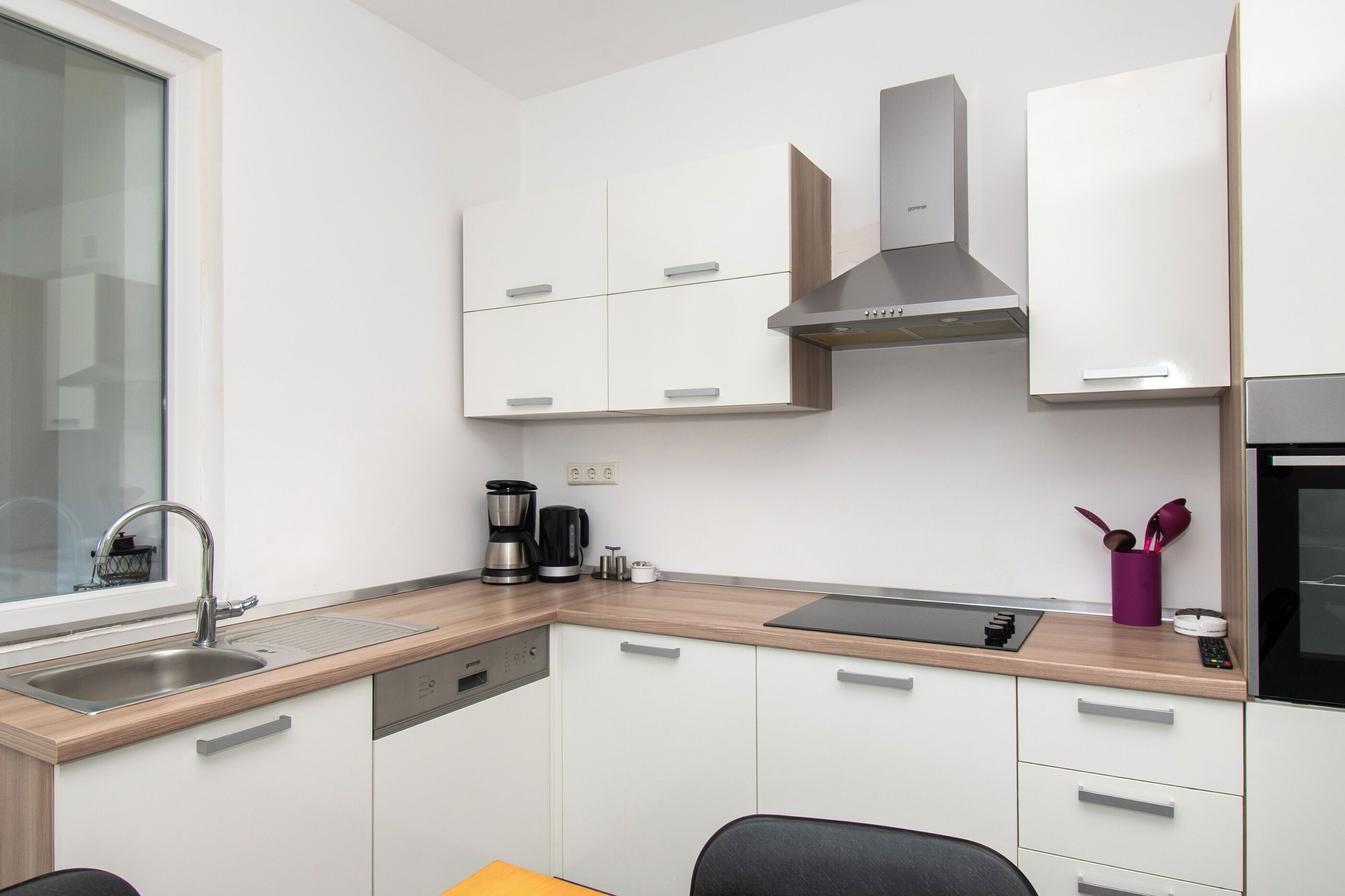 A modern kitchen with a built-in dishwasher, a coffee maker, and a microwave.