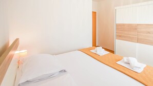 Ett hotellrum med en säng, ett träbord vid sängen, ett litet bord och en spegel.