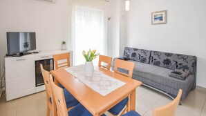 Ett modernt vardagsrum med ett matbord, stolar, en soffa, en tv och en liten växt.