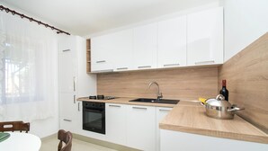Uma cozinha moderna com armários brancos, bancada de madeira, pia e fogão.