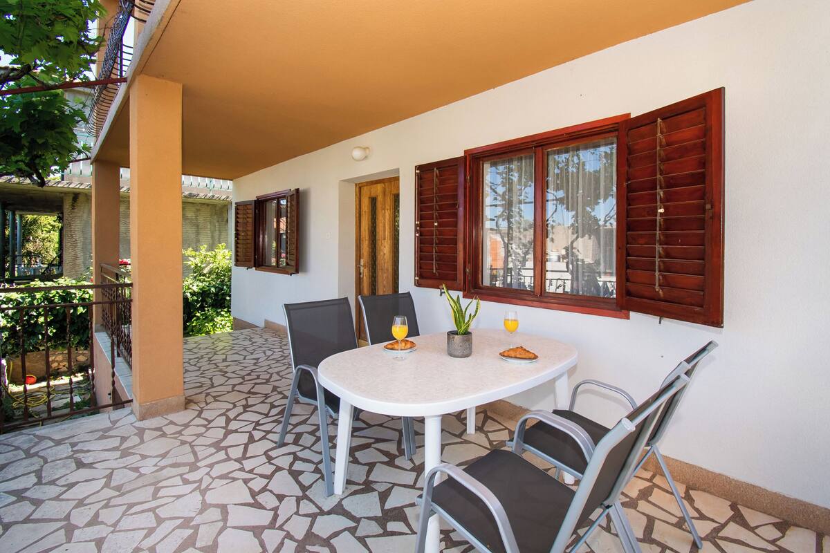 A patio with a round table, chairs, and wooden shutters.