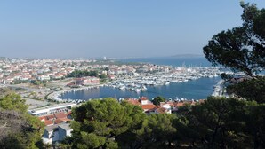 A coastal town with a marina, buildings with red roofs, and a clear blue sky. - Apartments Nena (Tribunj)