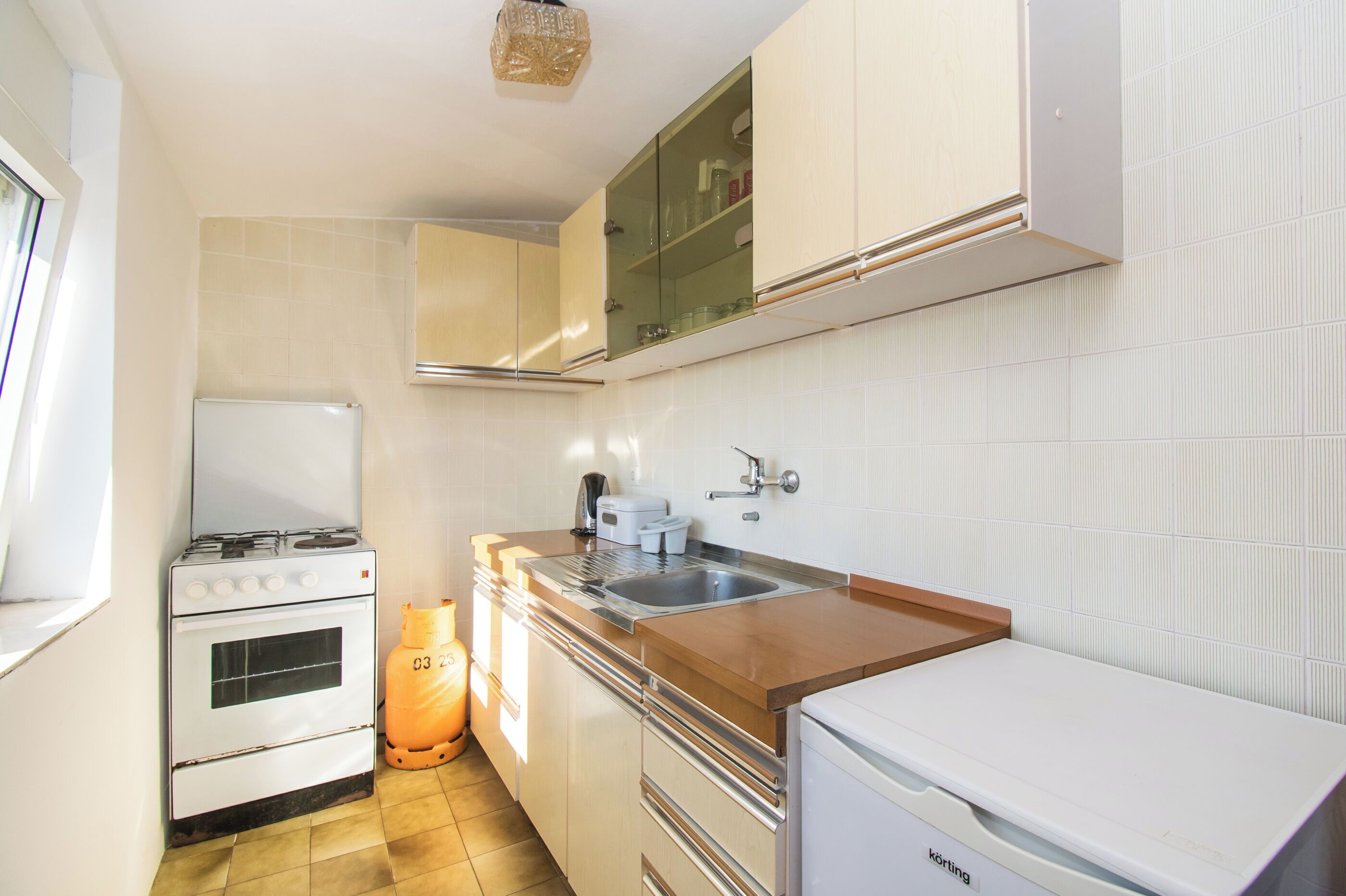 A compact kitchen with a stove, sink, and cabinets.