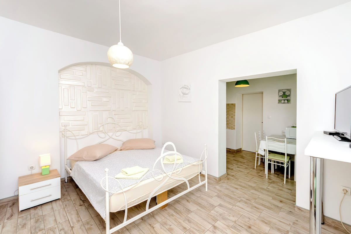 A bedroom with a bed, bedside table, and a desk area.