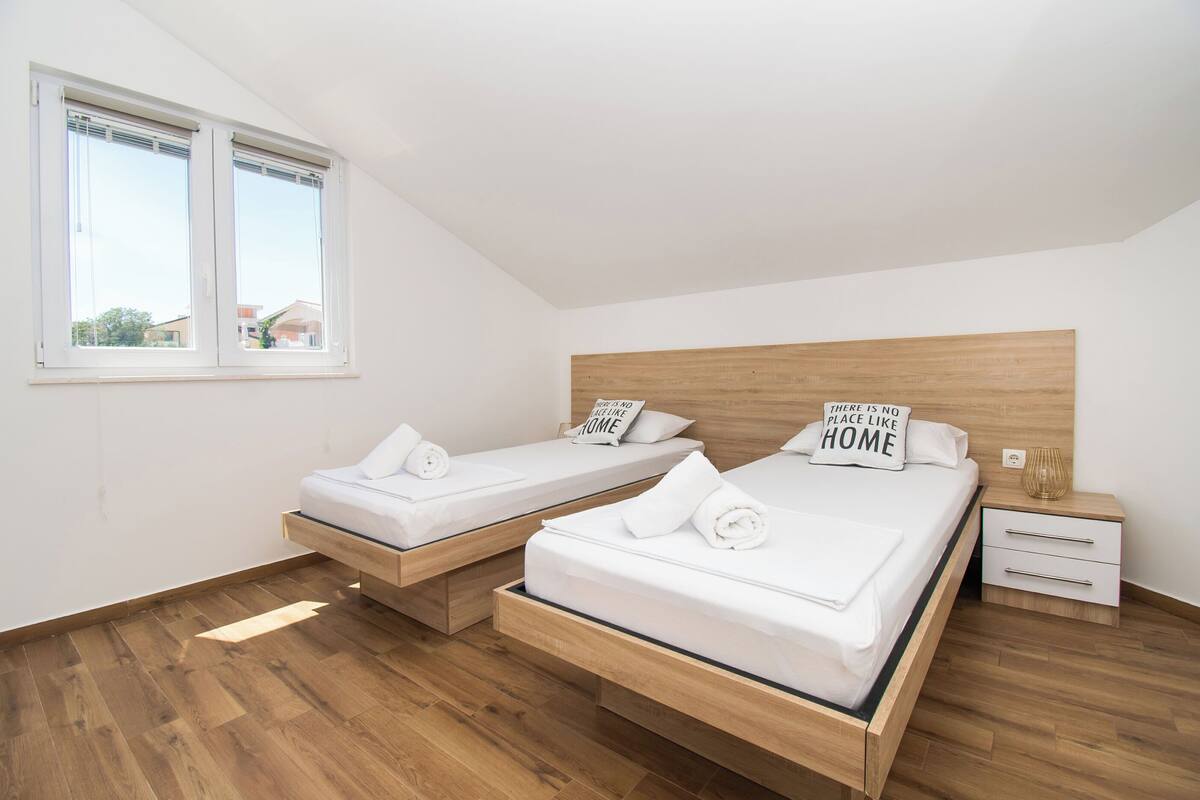 A room with two wooden beds, a nightstand, and a window.