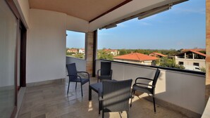 Un balcón con dos sillas y una mesa, con vista a una zona residencial de casas con tejados rojos.