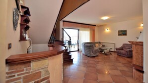 Amplia sala de estar con escalera, chimenea y una mesa de comedor.