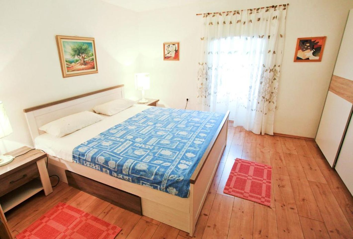 A bedroom with a bed, nightstand, and a window with curtains.