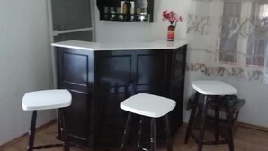 A kitchen with a white countertop, two stools, and a shelf with bottles. - House Golovik (Moscenicka Draga)
