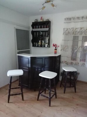 A kitchen with a white countertop, two stools, and a shelf with bottles. - House Golovik (Moscenicka Draga)