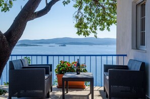 A balcony with wicker furniture, a table with a bottle and glasses, and a potted plant. - House Deja Blue (Orebic)