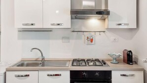 Una cocina moderna con armarios blancos, electrodomésticos de acero inoxidable, una estufa a gas y un lavamanos.