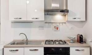 Une cuisine moderne avec des meubles blancs, des appareils en acier inoxydable, une cuisinière à gaz et un évier.