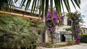 A building with a stone facade, arched windows, and a balcony with yellow and white railings. - Apartments Natasa (Rovinj)