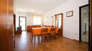 A dining area with a long table, chairs, and a sofa in the background. - Apartments Natasa (Rovinj)