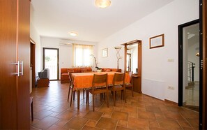 A dining area with a long table, chairs, and a sofa in the background. - Apartments Natasa (Rovinj)