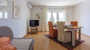 Una sala de estar moderna con comedor, que incluye un televisor de pantalla plana, un sofá y una mesa de comedor con sillas.