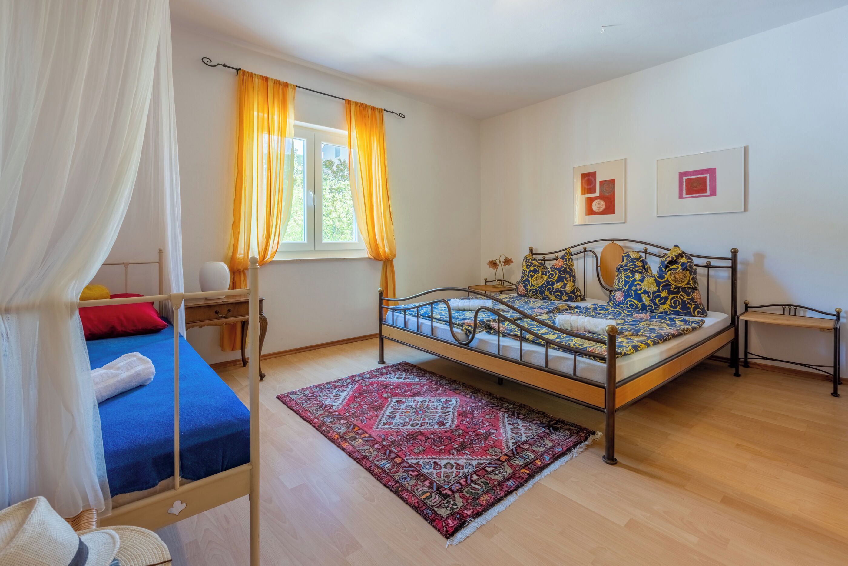 Una camera da letto con un letto, una finestra con tende, un comodino e un tappeto.