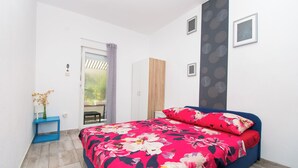 Una camera da letto con un letto, un armadio, un tavolino con un vaso e una porta che dà su un balcone.