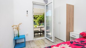 Una camera da letto con un letto, un armadio, un tavolino con un vaso e una porta vetrata scorrevole che dà su un patio esterno.