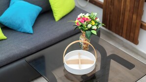 Un soggiorno moderno con un divano grigio, un tavolino in vetro e un piccolo vaso con fiori.