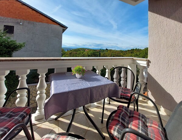 Een balkon met een tafel, stoelen en een bloempot.