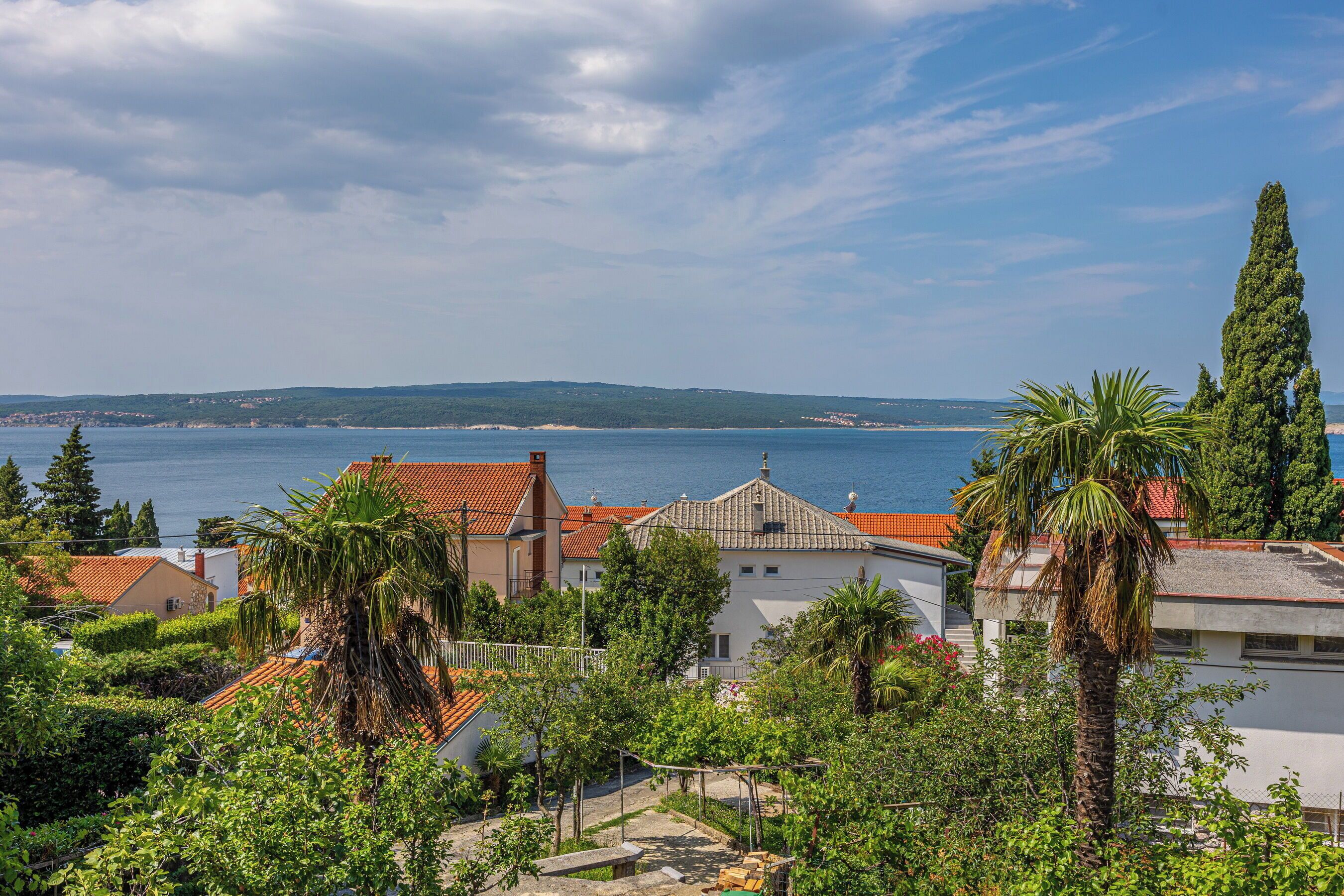 Un quartier résidentiel situé sur la côte, avec des maisons, une vue dégagée sur la mer et un paysage vallonné en arrière-plan.