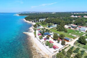 An aerial view of a coastal area with a beach, residential buildings, and greenery. - Mobile Home Kastanjola (Biograd na Moru)
