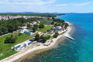 An aerial view of a coastal residential area with houses, a beach, and clear blue waters. - Mobile Home Kastanjola (Biograd na Moru)