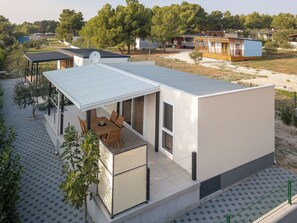 A modern house with a covered patio, a dining area, and a view of the surrounding landscape. - Mobile Home Kastanjola (Biograd na Moru)