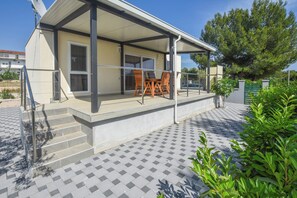 A covered outdoor area with a table and chairs, a staircase leading to a door, and a tiled patio. - Mobile Home Kastanjola (Biograd na Moru)
