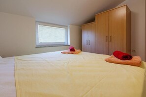 Ein Schlafzimmer mit einem Bett, einem Fenster mit Jalousien und einem Holzschrank.