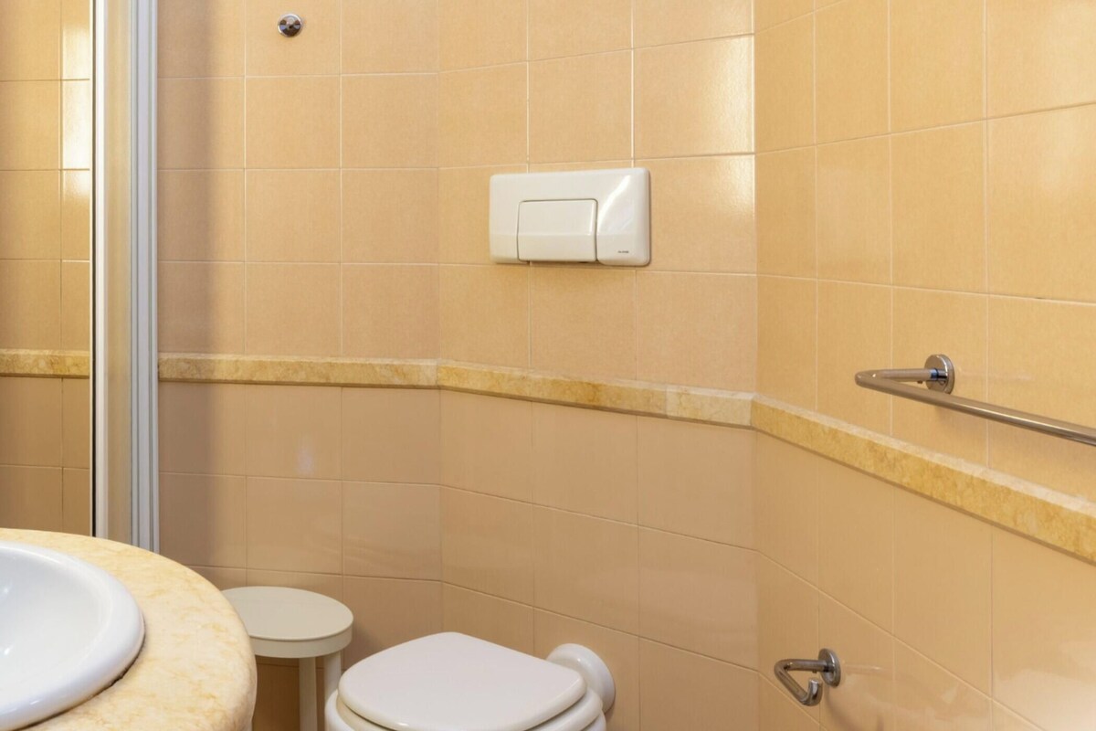 A bathroom with a toilet, sink, and shower area.