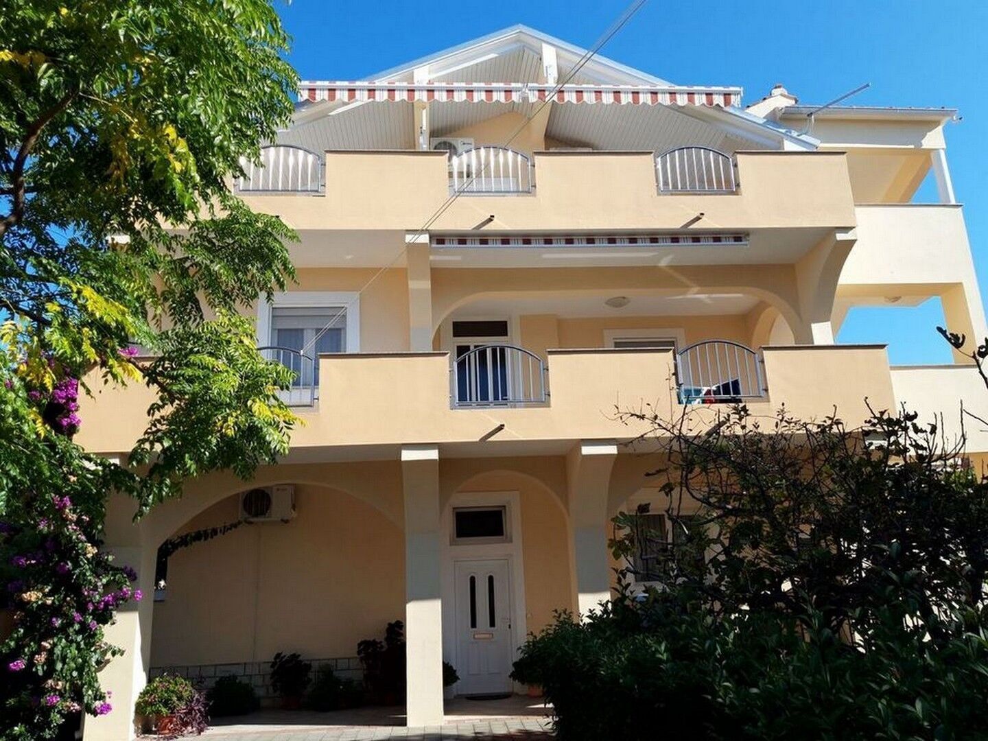A two-story building with a flat roof, balconies, and a central entrance.