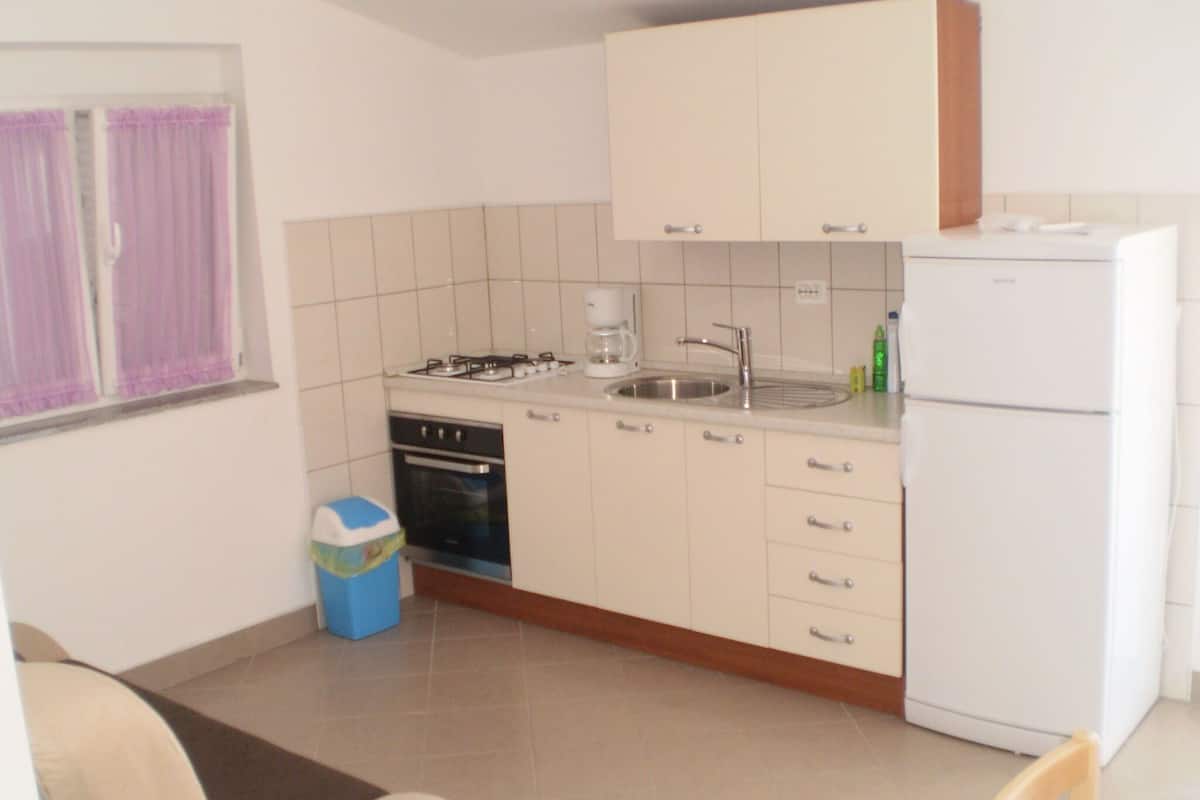 A compact kitchen with a gas stove, sink, and a white refrigerator.