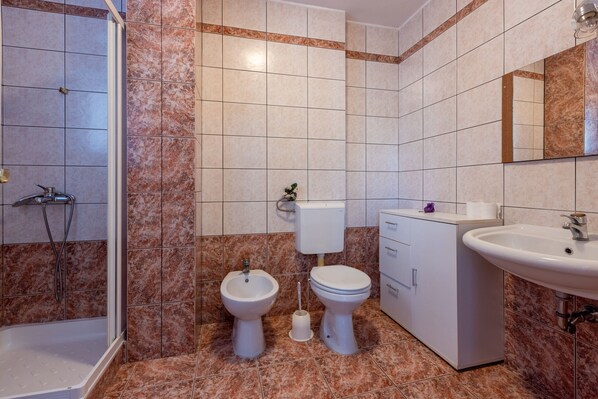 A bathroom with a shower, bidet, toilet, sink, and cabinet. - House Sunshine (Novi Vinodolski)