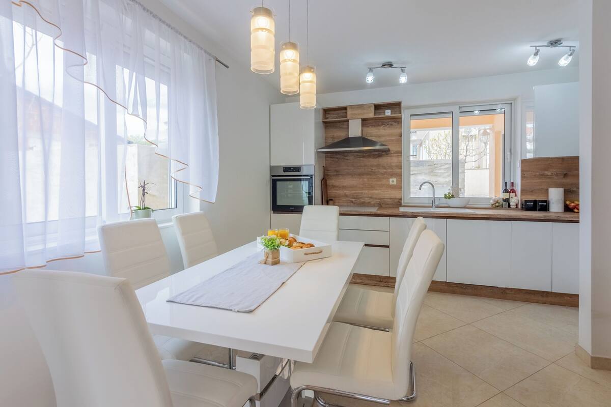 A modern kitchen with white cabinetry, a built-in oven, and a wooden accent wall.