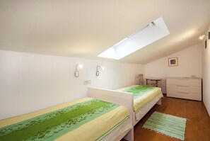 Ένα μικρό, καλά φωτισμένο δωμάτιο με δύο μονά κρεβάτια, ένα γραφείο και μια συρταριέρα.
