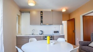 Una cucina compatta con un tavolo e sedie bianche, un forno a microonde e una macchina per il caffè.