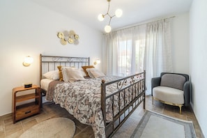 A bedroom with a bed, bedside tables, a chair, and a chandelier. - House Josipa (Supetar)