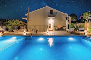 A swimming pool with lounge chairs and a building in the background. - House Josipa (Supetar)