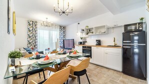 Een moderne keuken met een zwarte koelkast, witte kasten en een glazen eettafel.