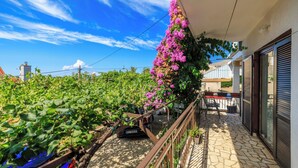 Ein Balkon mit Steinboden, Metallgeländer und Blick auf einen Weinberg.