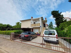 A two-story house with a balcony, a garage, and a gated driveway. - Apartments Katica (Crikvenica)