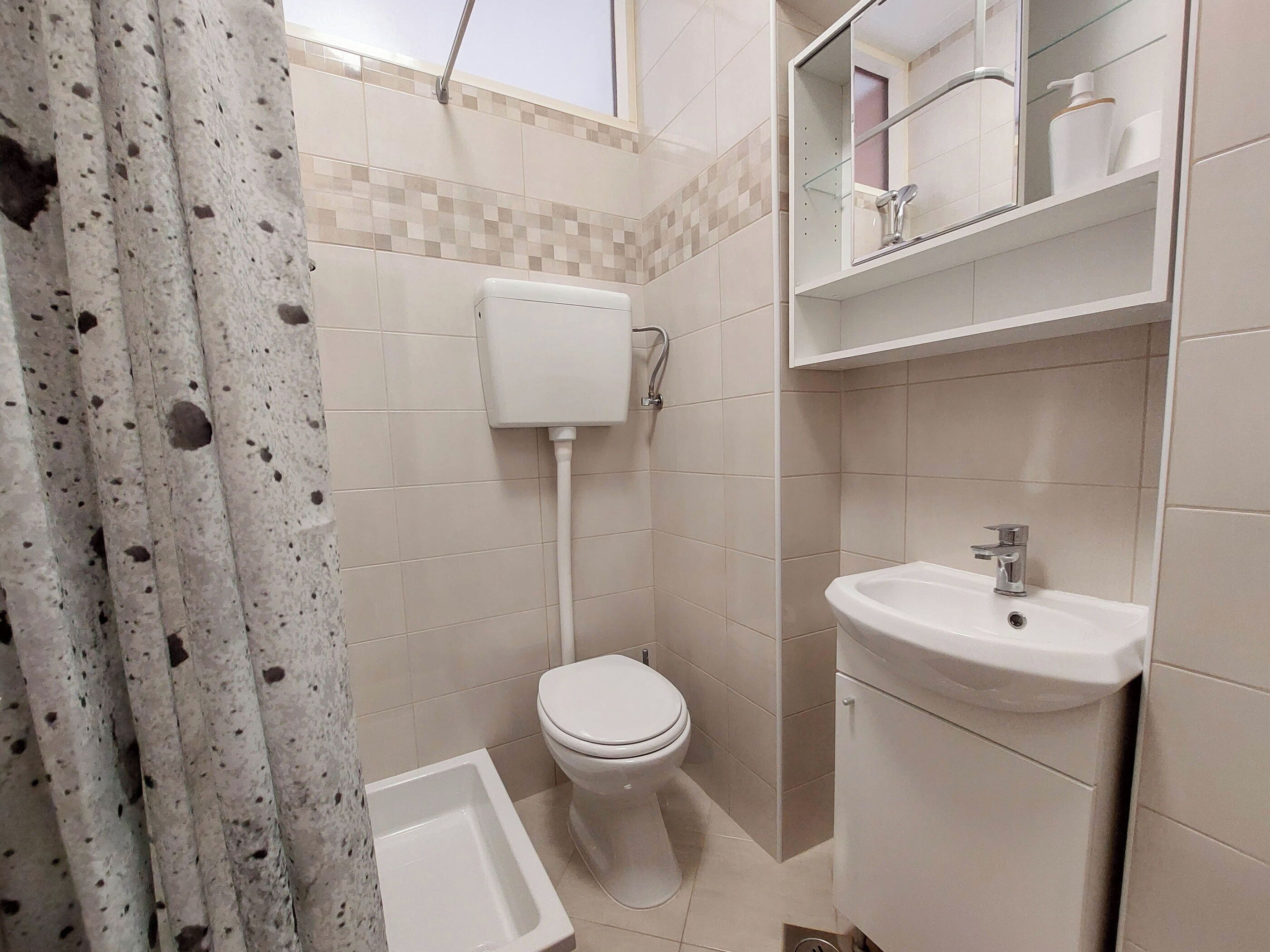 A bathroom with a toilet, sink, and shower curtain.