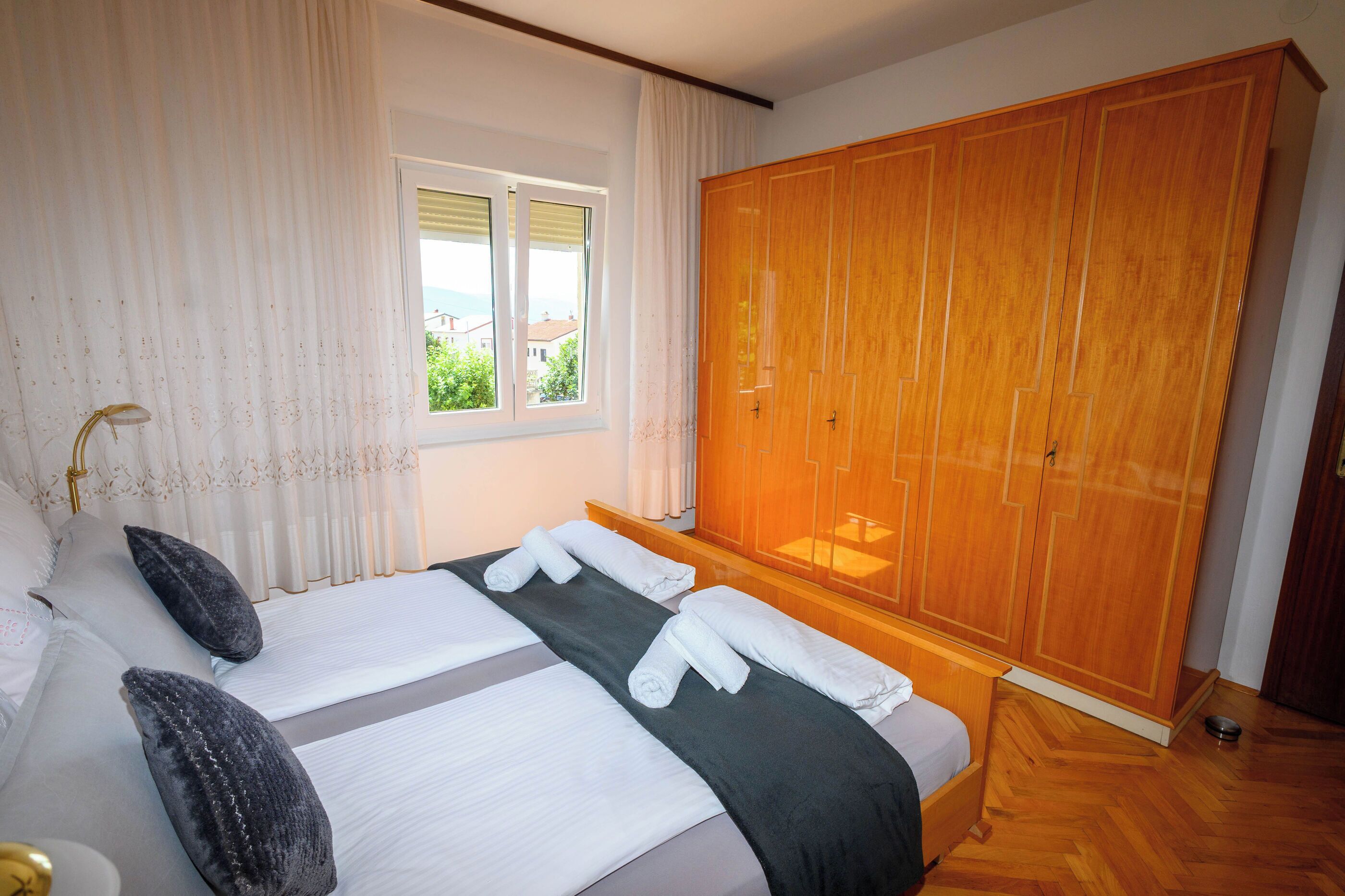 Een hotelkamer met een bed, een ruime kast, een raam met gordijnen en uitzicht op buiten.