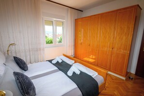 Ein Hotelzimmer mit einem Bett, einem großen Kleiderschrank, einem Fenster mit Vorhängen und Blick nach draußen.