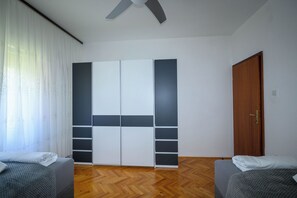 Een kamer met een kast, twee bedden, een houten deur en een plafondventilator.