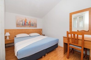 A bedroom with a bed, a desk, a chair, a nightstand, and a wall-mounted painting. - Apartments Anita Tribunj (Tribunj)